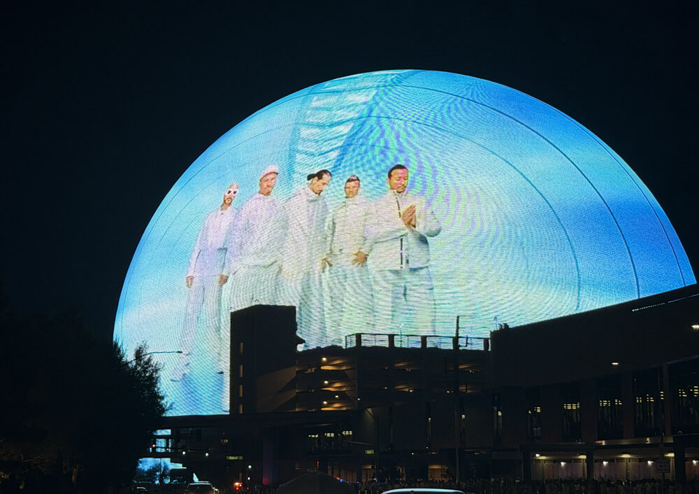 shot of the sphere against the night sky, the sphere is showing a photo of Backstreet Boys