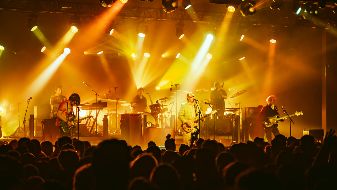 Modest Mouse on stage under yellow lighting