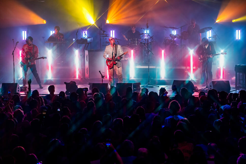 Modest Mouse on stage in front of colorful lights