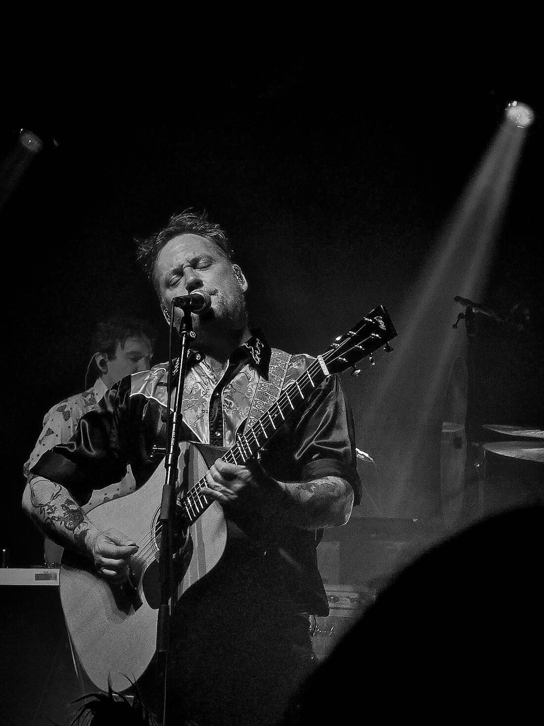 black and white shot of Isaac Brock playing guitar and wearing a silky cowboy shirt