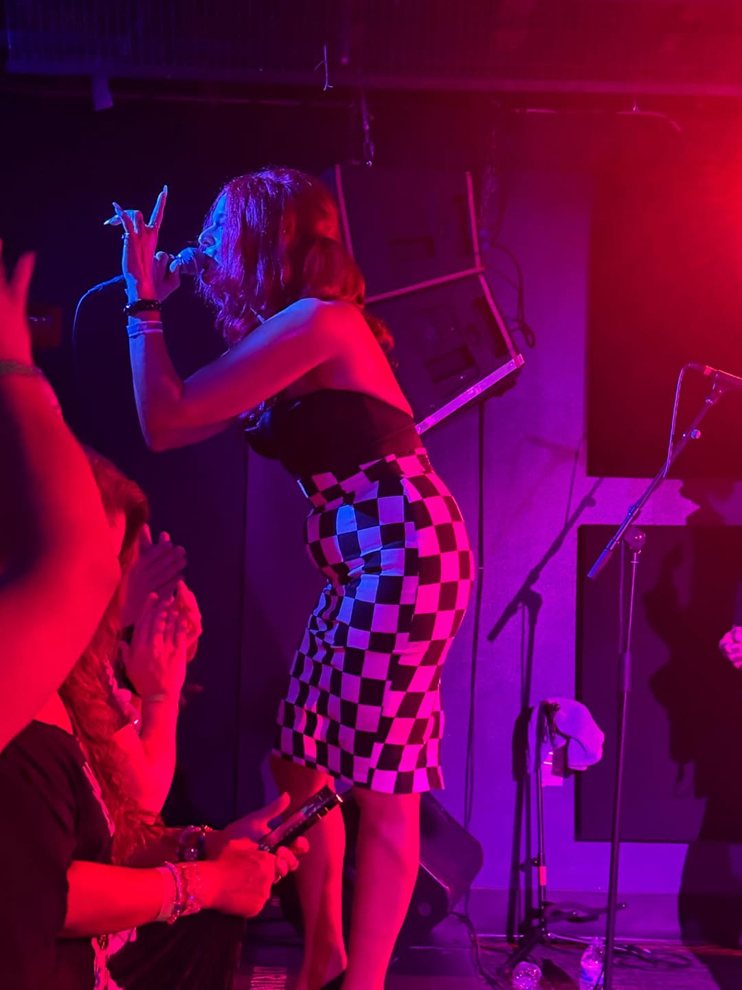 Monique Powell in a checkered skirt singing to the crowd