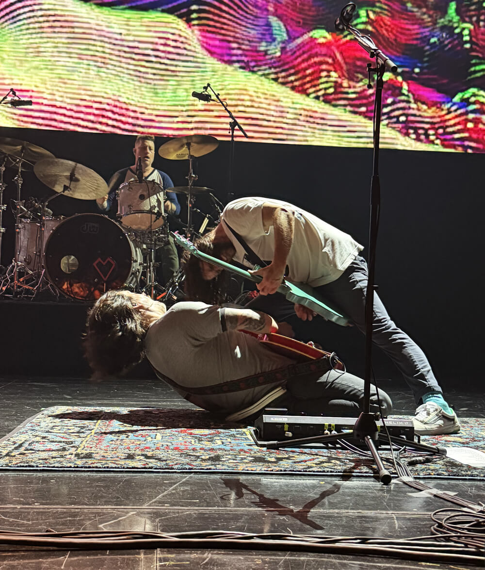 Mike and Nick jamming, Nick is kneeling way back on the ground and Mike is leaning over him
