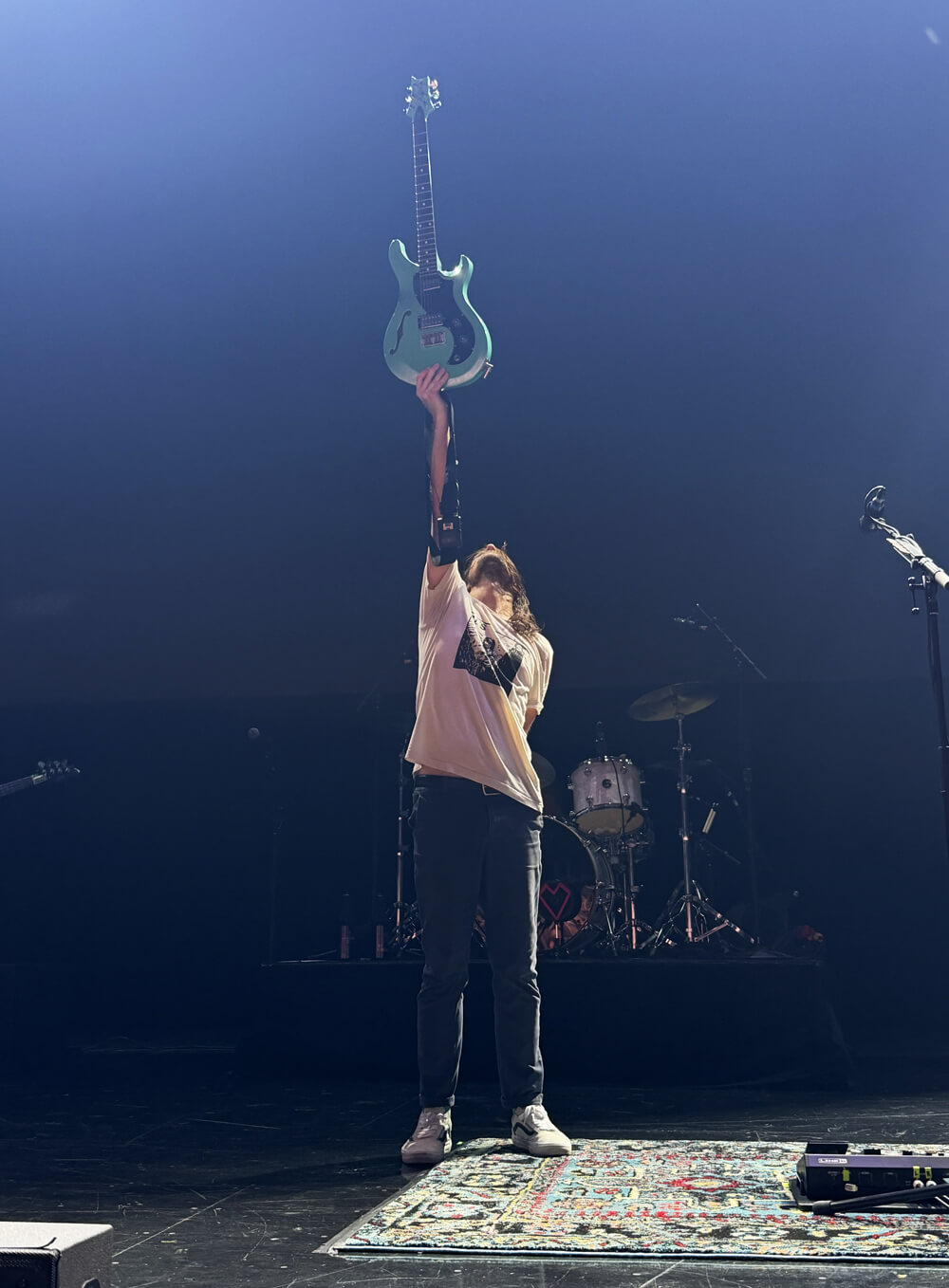 Mike holding his guitar straight up in the air
